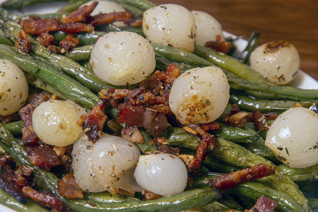 Close up of green beans bacon and pearl onions plated