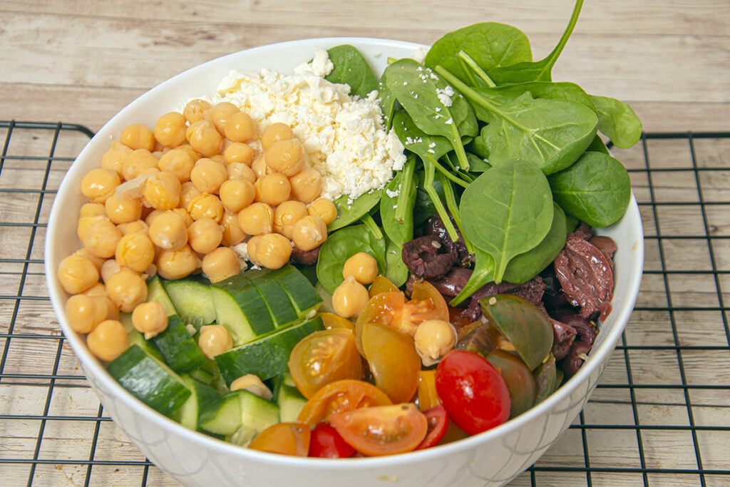 Assembling your vegan Greek quinoa bowl