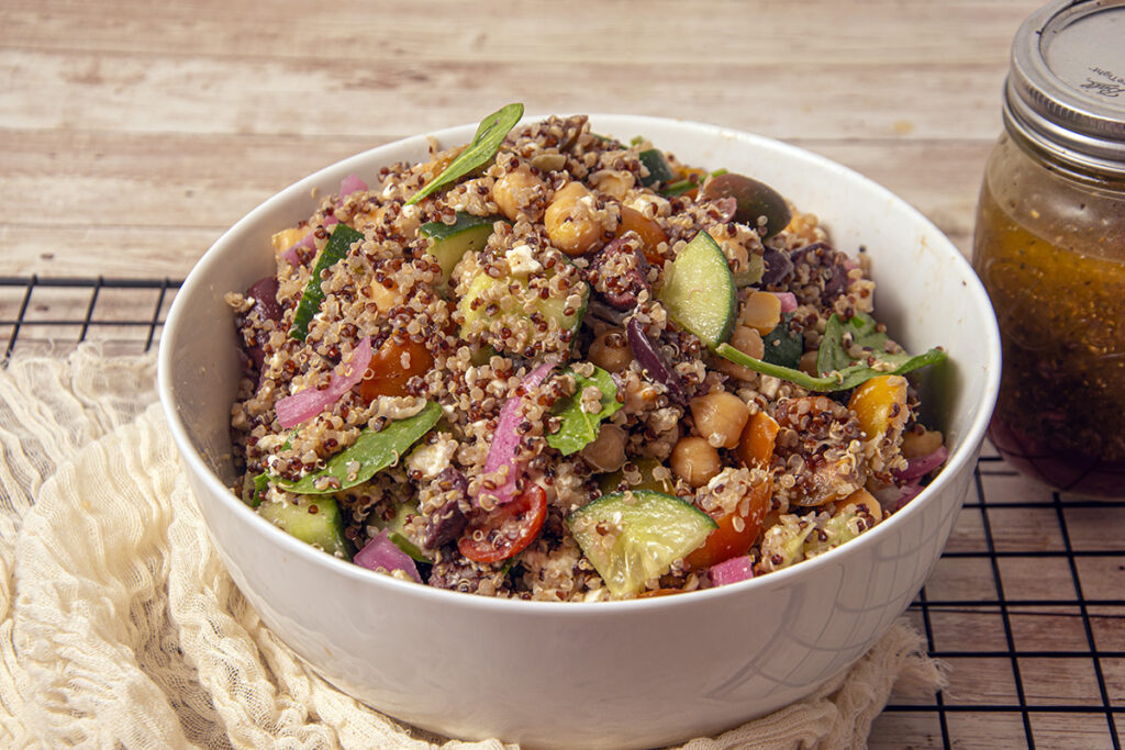 Greek quinoa salad bowl with Greek dressing in the side.