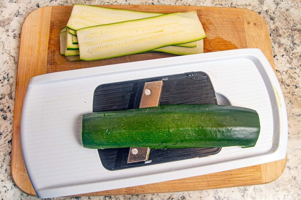 Using a mandoline to slice the zucchini thin.