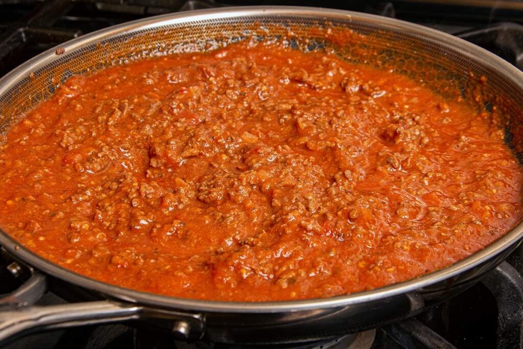 Adding the tomato sauce to the meat to create a delicious meat sauce.